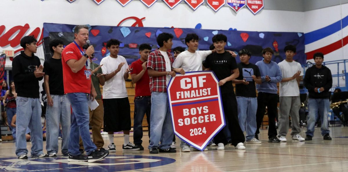 Al final… Dave Musatti recognizes the boys soccer team at the battle of the patriots rally for making it to the final round of CIF. 
“I was happy to receive the banner it's another memory being left for the school,” Ismael Zavala, 11, said. 
The soccer team stood up all together, did a cheer and received a banner that would be hung up in the gym for all their hard work. Photo By Azul Rios.