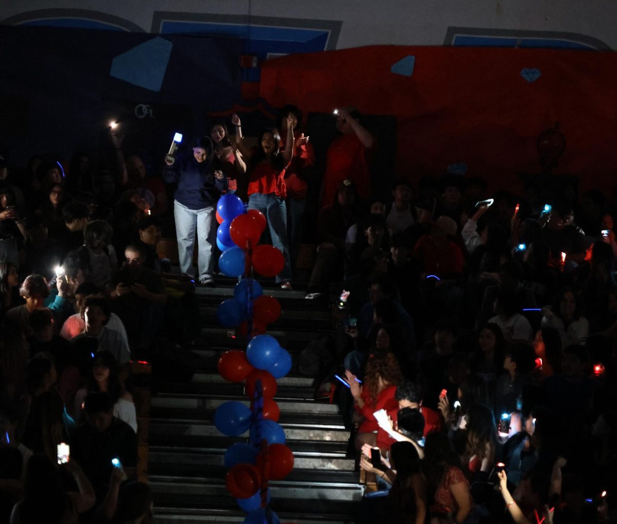 Lights out! Liz Gudino, 11, and Joselin Garcia, 11, cheer as they walk down the stairs for their respective teams. Gudino was in the red team and Garcia was in blue.   
“I was so excited to get the torch, I really wanted to win and I got the chance,” Gudino said.
Gudino was full of excitement to receive the torch because she is a Torch yearbook editor. Photo by Jessica Young.
