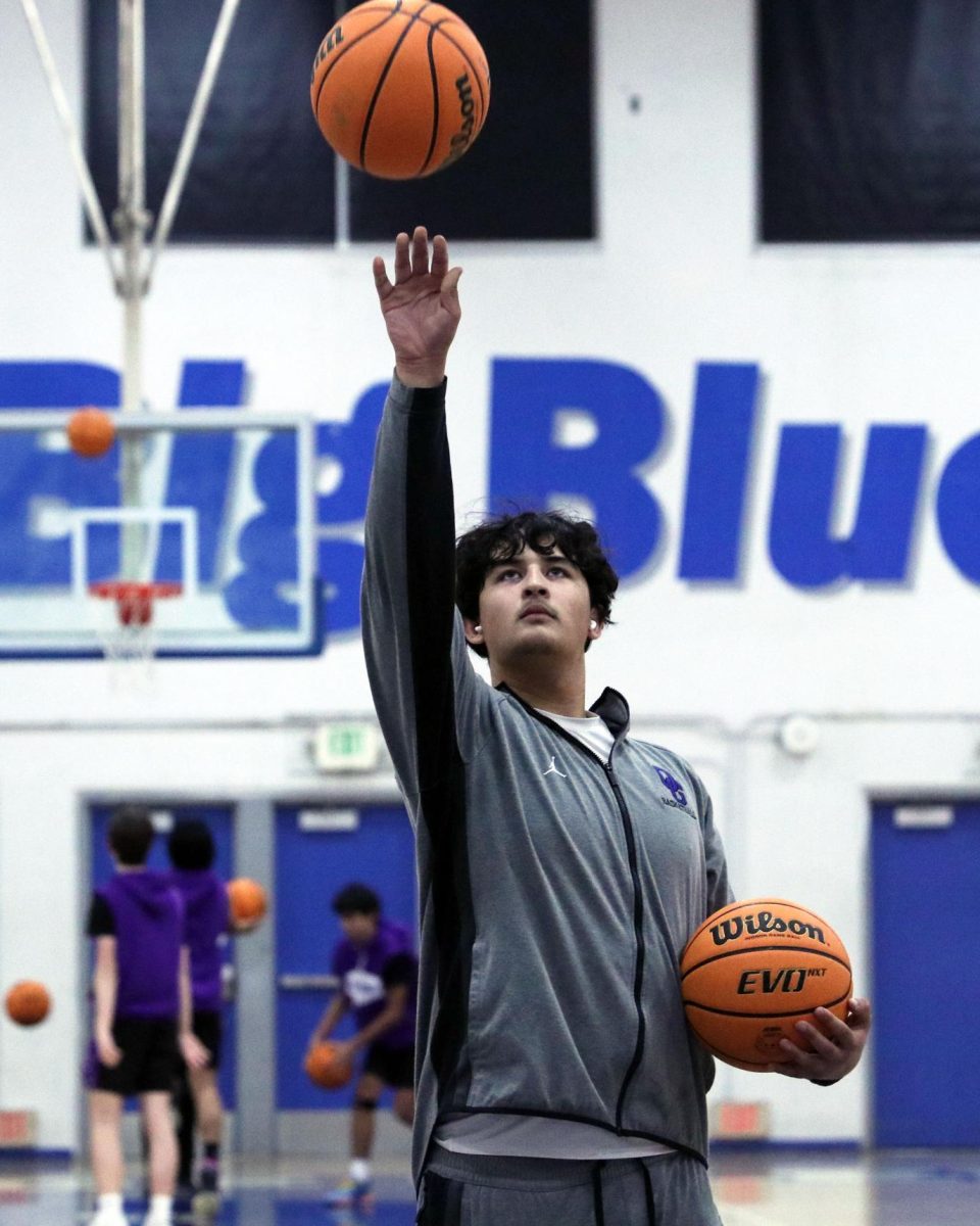 Dialed in. Completely focused on the ball, Noah Reynoso, 12, listens to music while practicing his shots. Before the boys basketball team played against Rock Academy, the players met up in the main gym to practice and warm up all together. “I listen to music while I'm warming up. I think it helps me dial in and drown out all the other thoughts for anything else,” Reynoso said. He felt like music has become an important part of his warm up routine. Photo by Amber Cardenas.