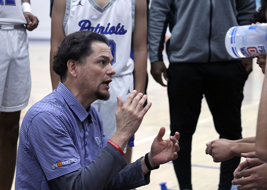 Listen up! In between the cluster, Varsity Basketball coach Roman Macias, gathers the Boys Basketball team to review key points before a game. Before the game against Rock Academy the Boys Basketball team got the chance to pray and encourage each other before receiving encouragement from their coaches. “I think our coach supports us pretty well. He never brings us down. He always hypes us up,” Varsity Player Noah Reynoso, 12, said. Varsity Basketball Assistant coach, Brian Gallo felt the long time friendship between the coaches has helped them have strong communication in order to effectively support their team. Photo by Amber Cardenas.