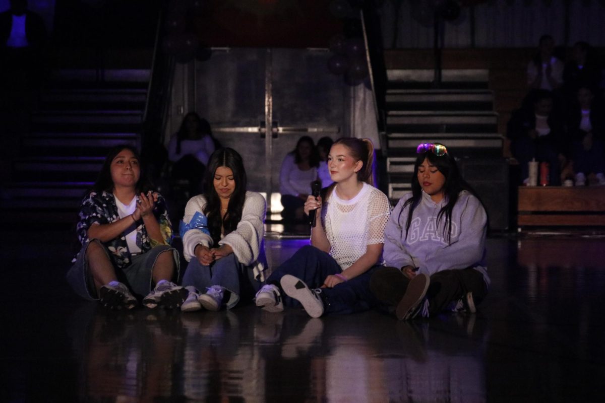 Bringing The Spirit. As the gym went quiet and the lights turned on. The Emcees Carla Andrade, 12, Joselin Garcia, 12, Vanessa Morelos, 12, and Colbie Argento, 11,  gathered around to start riling up the crowd. They started by talking between themselves and introducing the pep rally, welcome everyone, help transition the spirit to sports, announcements, games and performances. “I am usually a talkative person but I feel like when I am up there in front of everyone I put all my nerves into more energy,” Colbie Argento, 11, said . Before the rally, the emcees spend time going over what they are going to say, practice between themselves, and focus on their energy.  Photo by Ernie Soliz. 